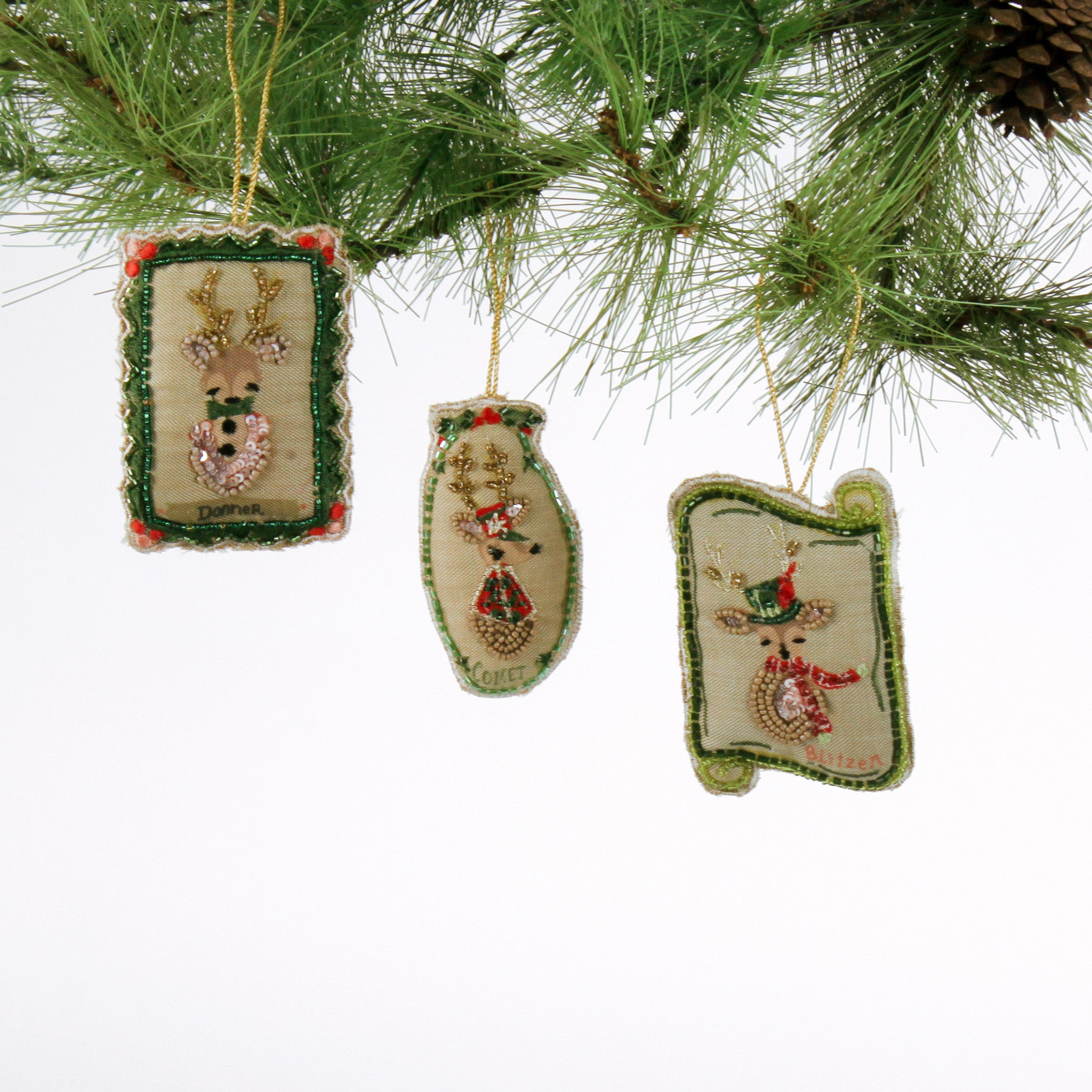 Group of Hand Painted Beaded Reindeer Christmas Ornaments Donner, Comet, and Blitzen hanging on pine.