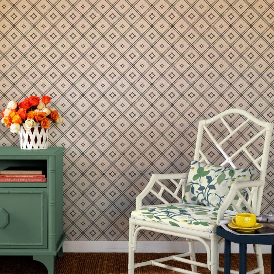 a white chair in front of a navy bamboo trellis wallpaper design on a white background from Madcap Cottage.