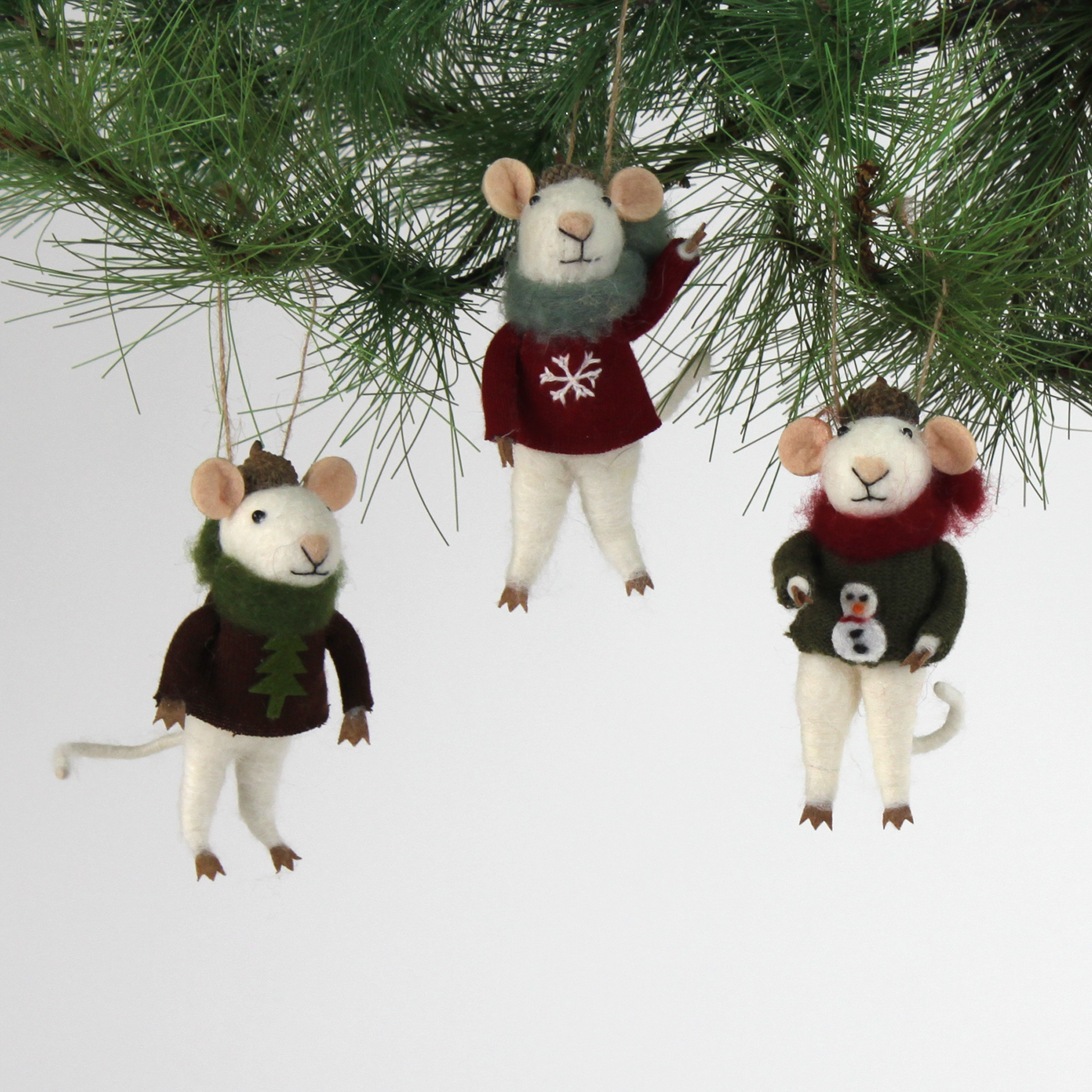 Three felt mouse ornaments wearing cozy sweaters with festive designs—a snowman, a tree, and a snowflake—each topped with a tiny acorn cap and ready to hang.