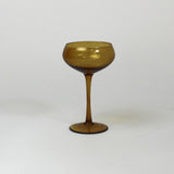 an amber colored coupe glass on a white background