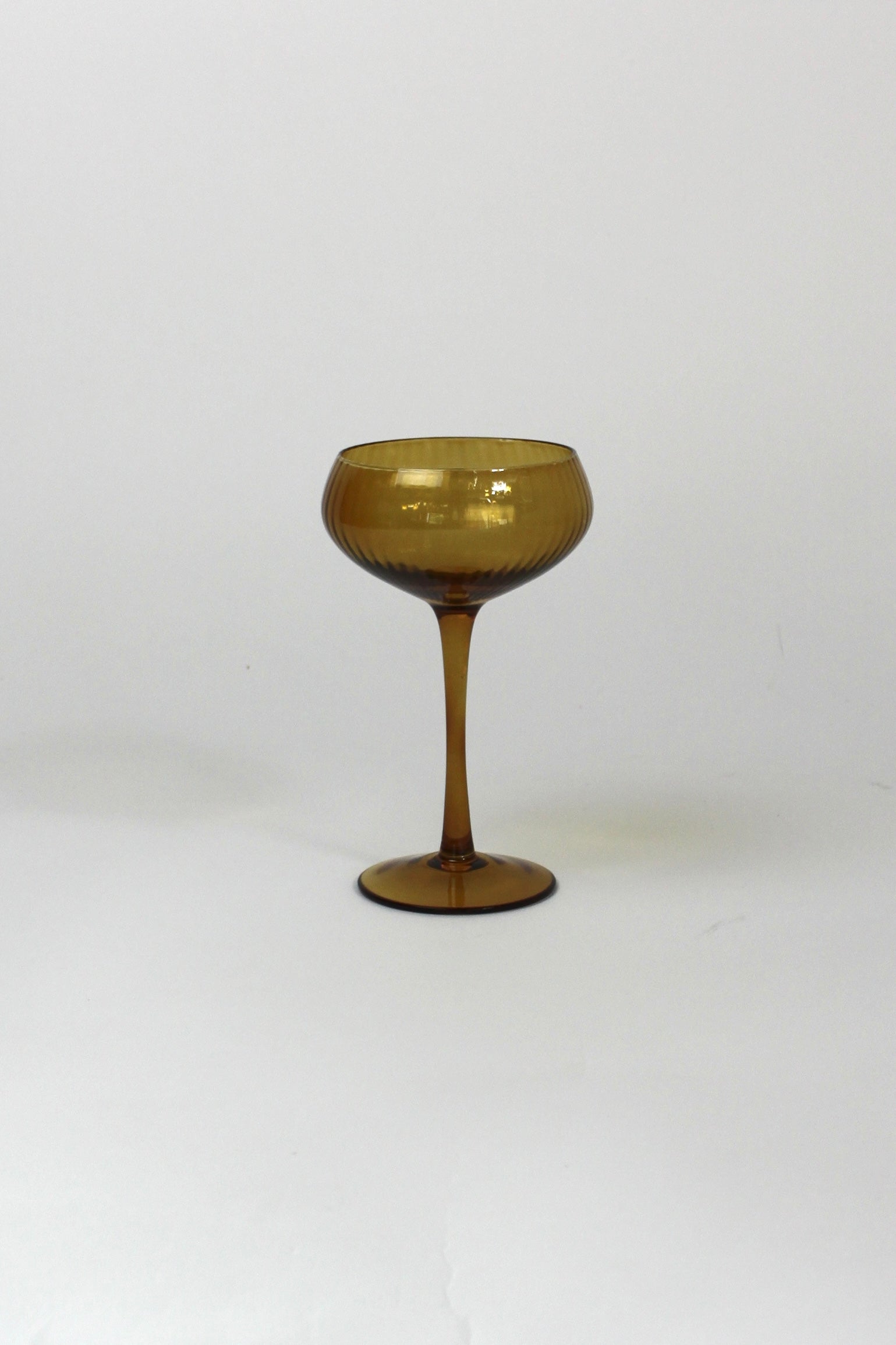 an amber colored coupe glass on a white background