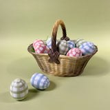 a basket filled with tole metal large decorative easter eggs printed with a gingham pattern.