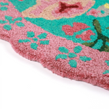 close up details of A pink and green floral rug featuring a scalloped border and large central pug motif
