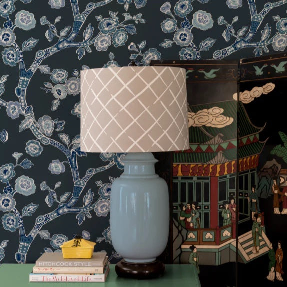 A blue lamp and oriental screen against a wall of navy blue and white chinoiserie wallpaper