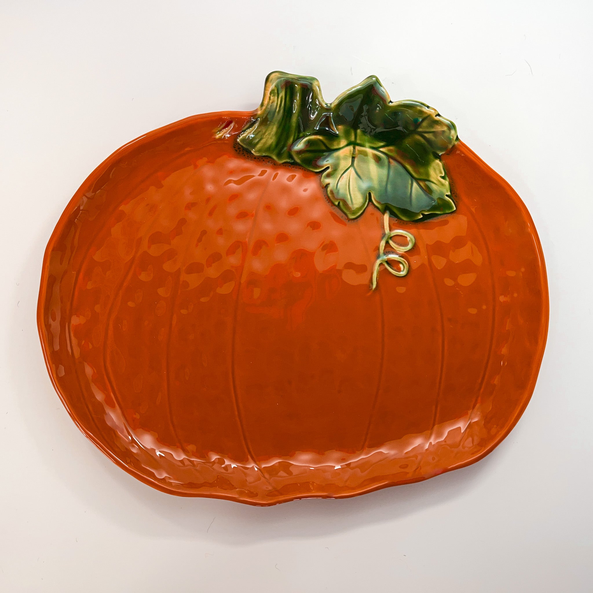 a large orange pumpkin serving platter against a white background