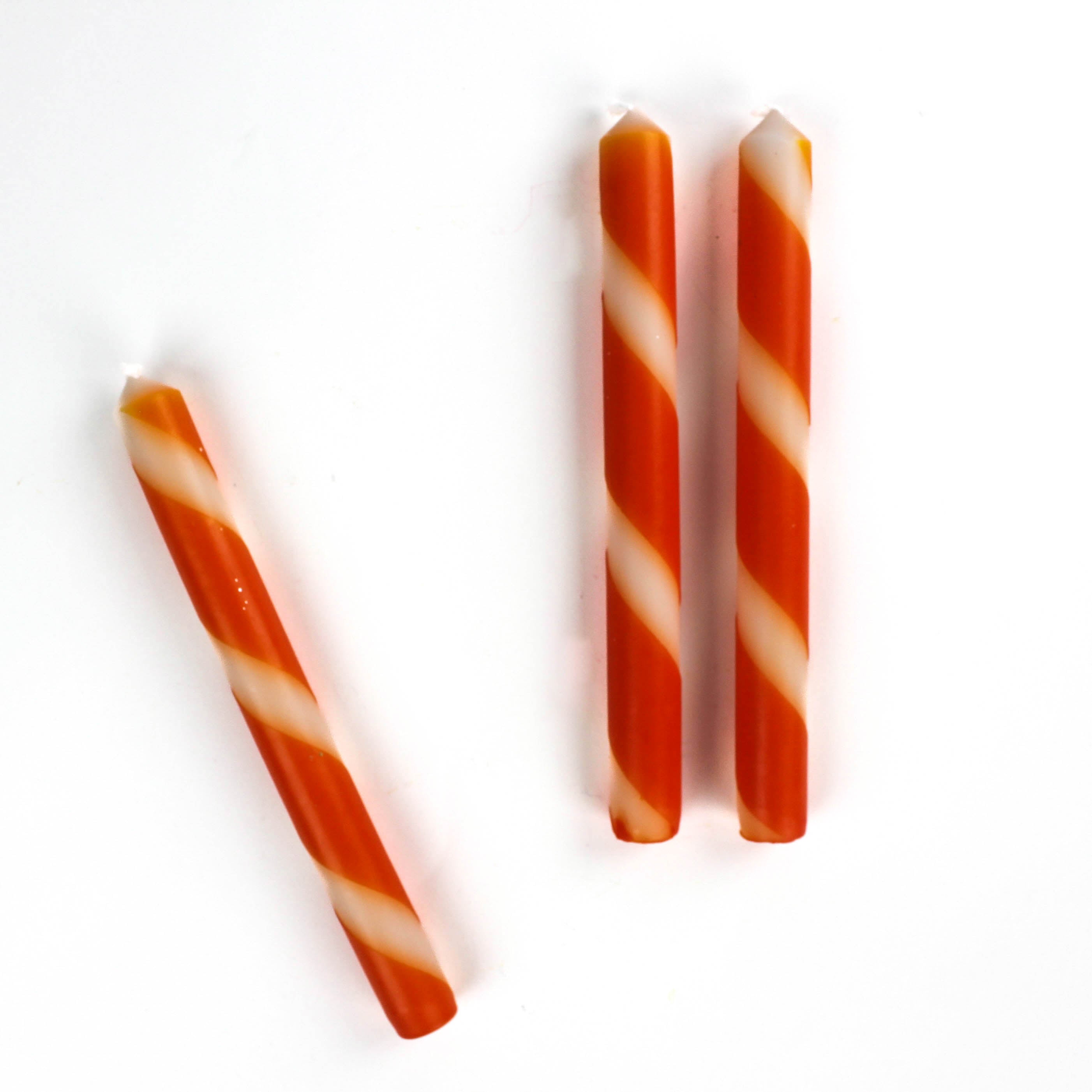 Three orange and white stripe taper candles.