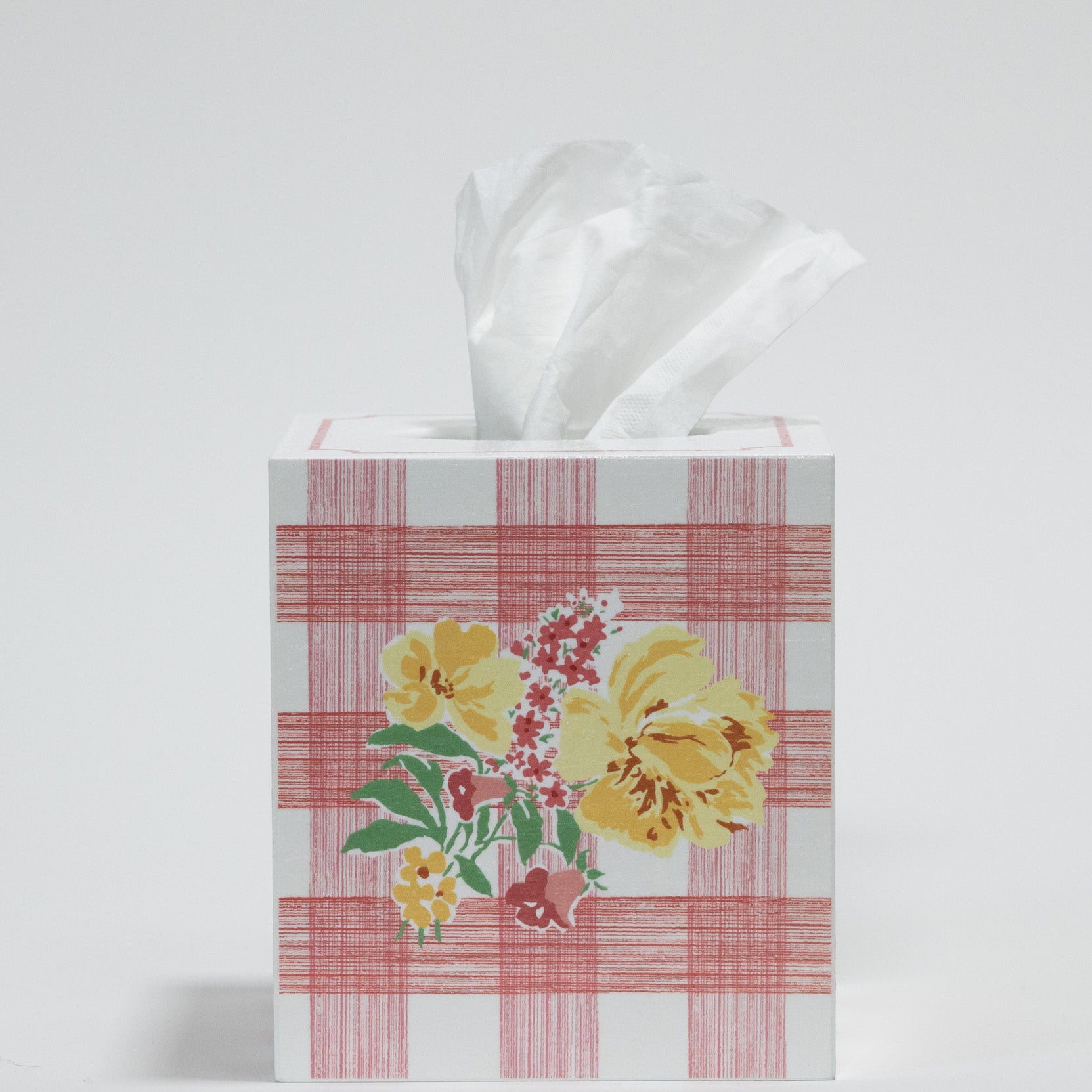 a pink gingham tissue box cover with a central yellow floral motif on the front.