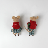 back of Two felt mouse ornaments wear festive red jackets and blue-green clothing—one holding a teddy bear and the other carrying a holiday wreath—lying flat
