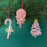 Set of three colorful candy-themed Christmas ornaments shaped like candy canes, lollipops, and Christmas trees