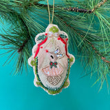 Hand Painted Beaded Dancer Reindeer Christmas Ornament hanging on pine branch with green background.