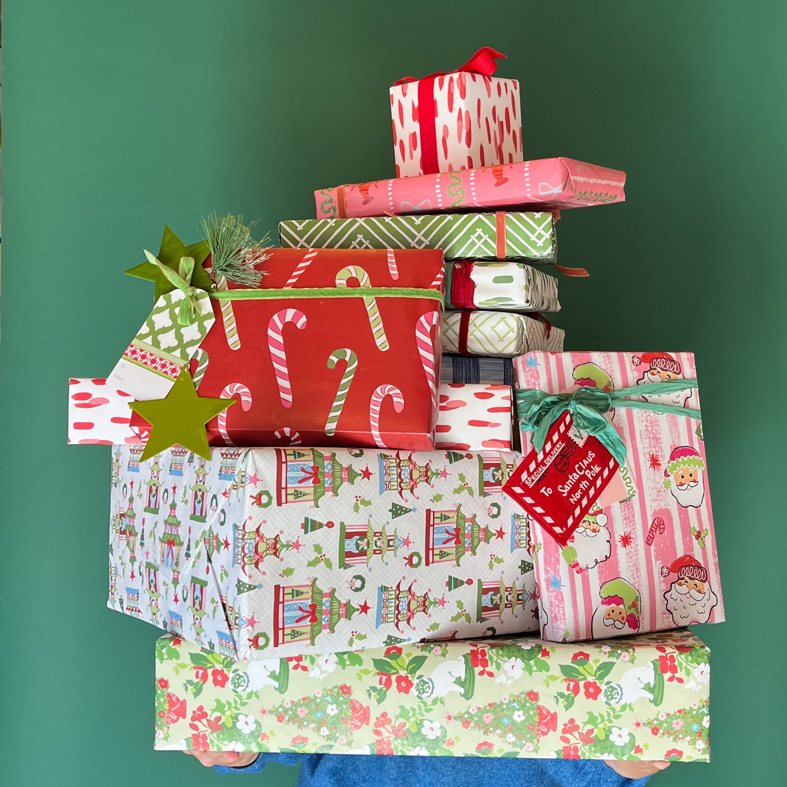 A pile of gifts wrapped in Madcap Cottage colorful Christmas wrapping paper