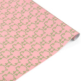 Rolled elegant gift wrapping paper featuring intricate green bamboo lattice patterns on a soft pink background.