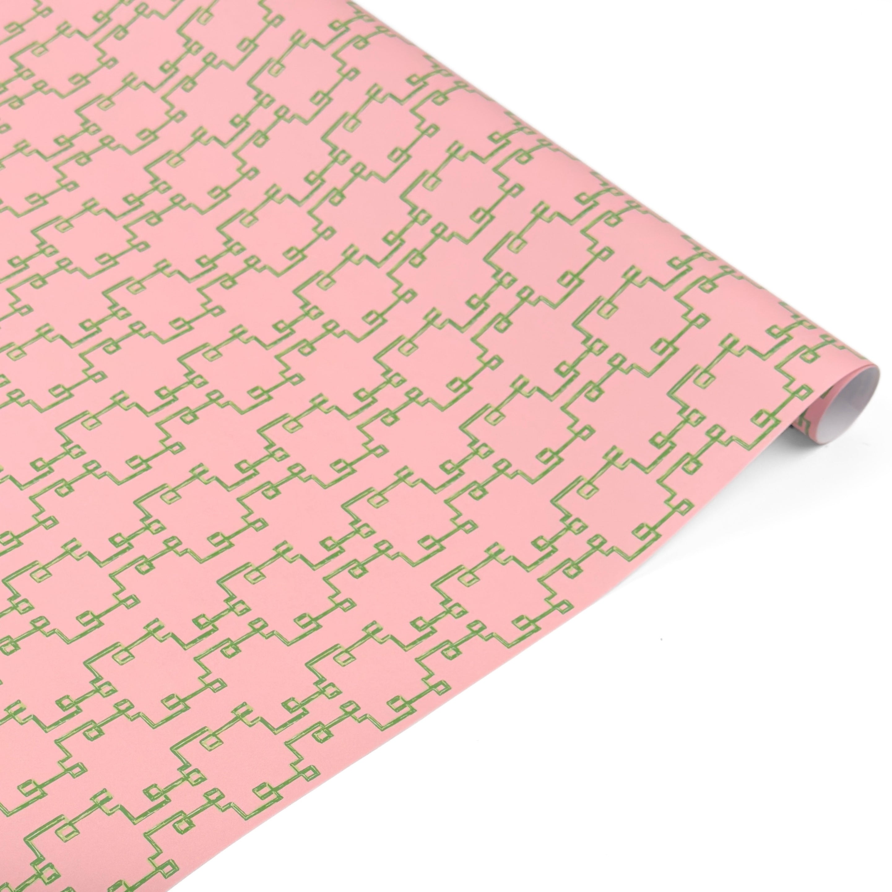 Rolled elegant gift wrapping paper featuring intricate green bamboo lattice patterns on a soft pink background.
