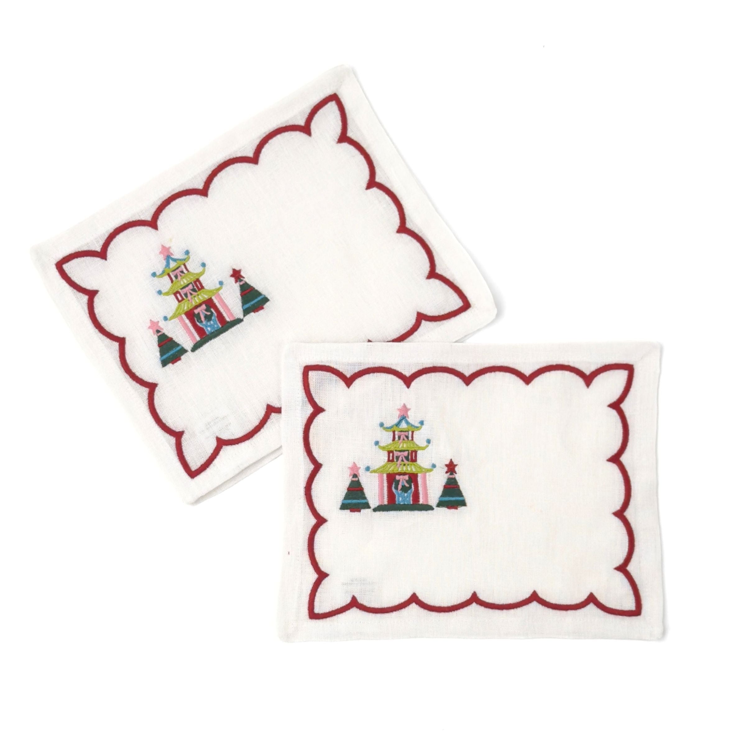 Elegant white cocktail napkins featuring red scalloped borders, colorful Christmas pagodas, festive trees, and embroidery.