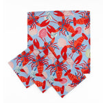 Set of Blue cloth dinner napkins featuring vibrant red lobsters, seashells, and playful coastal patterns for entertaining.