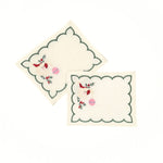 Elegant white cocktail napkins featuring green scalloped borders, embroidered Santa faces, holly, and pink ornaments.