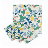 Set of White cloth dinner napkins featuring vibrant strawberries, yellow lemons, blue flowers, and lush green foliage.