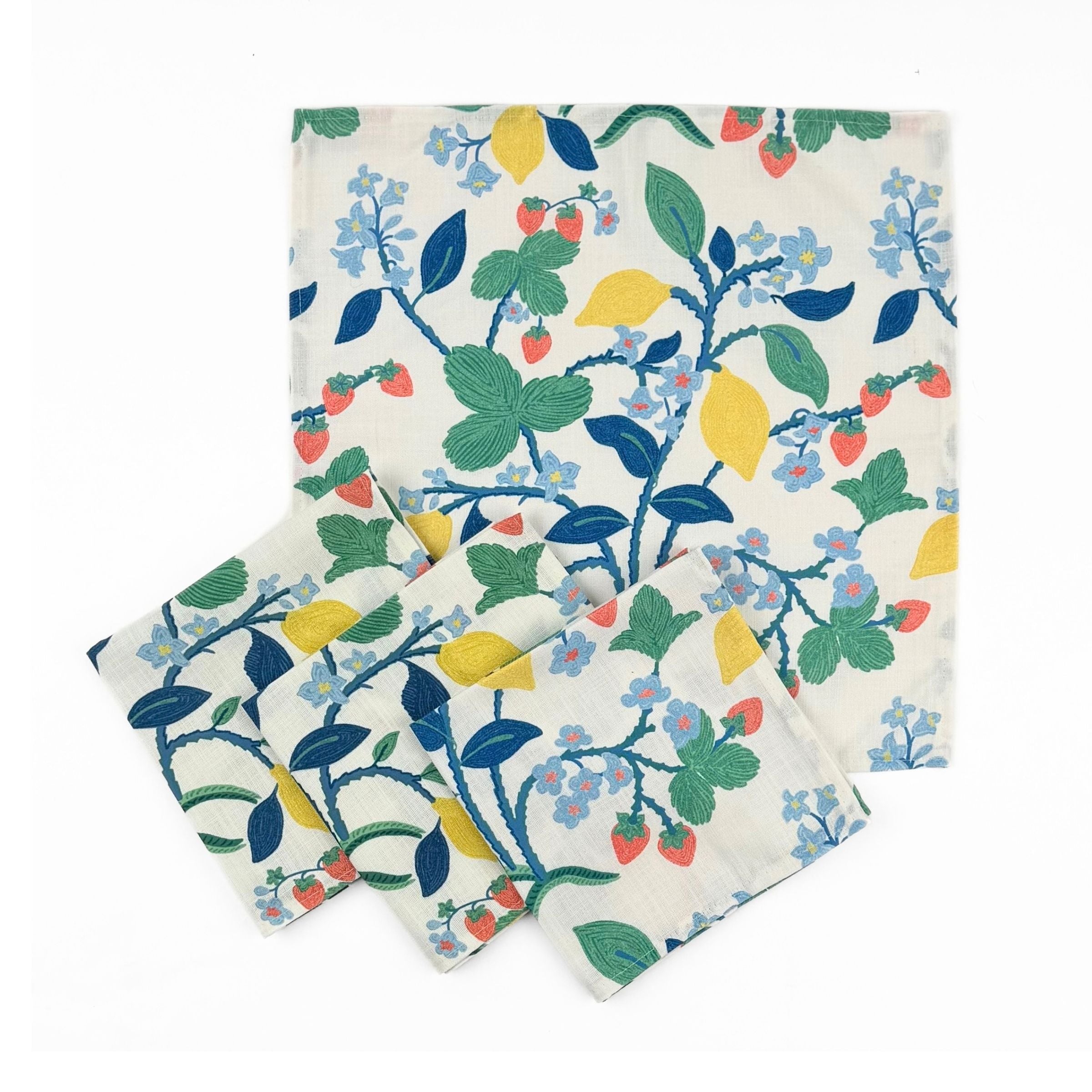 Set of White cloth dinner napkins featuring vibrant strawberries, yellow lemons, blue flowers, and lush green foliage.