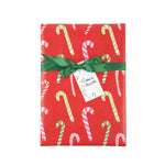 A rectangular gift box wrapped in festive red paper with a candy cane pattern, tied with a green ribbon and a small white gift tag.