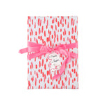 a gift wrapped in gift wrap with a pink brushstroke pattern design, tied with a pink bow. 