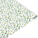 A roll of wrapping paper with a white background and a pattern of small, irregular green and light yellow brushstrokes, shown partially unrolled on a white background.
