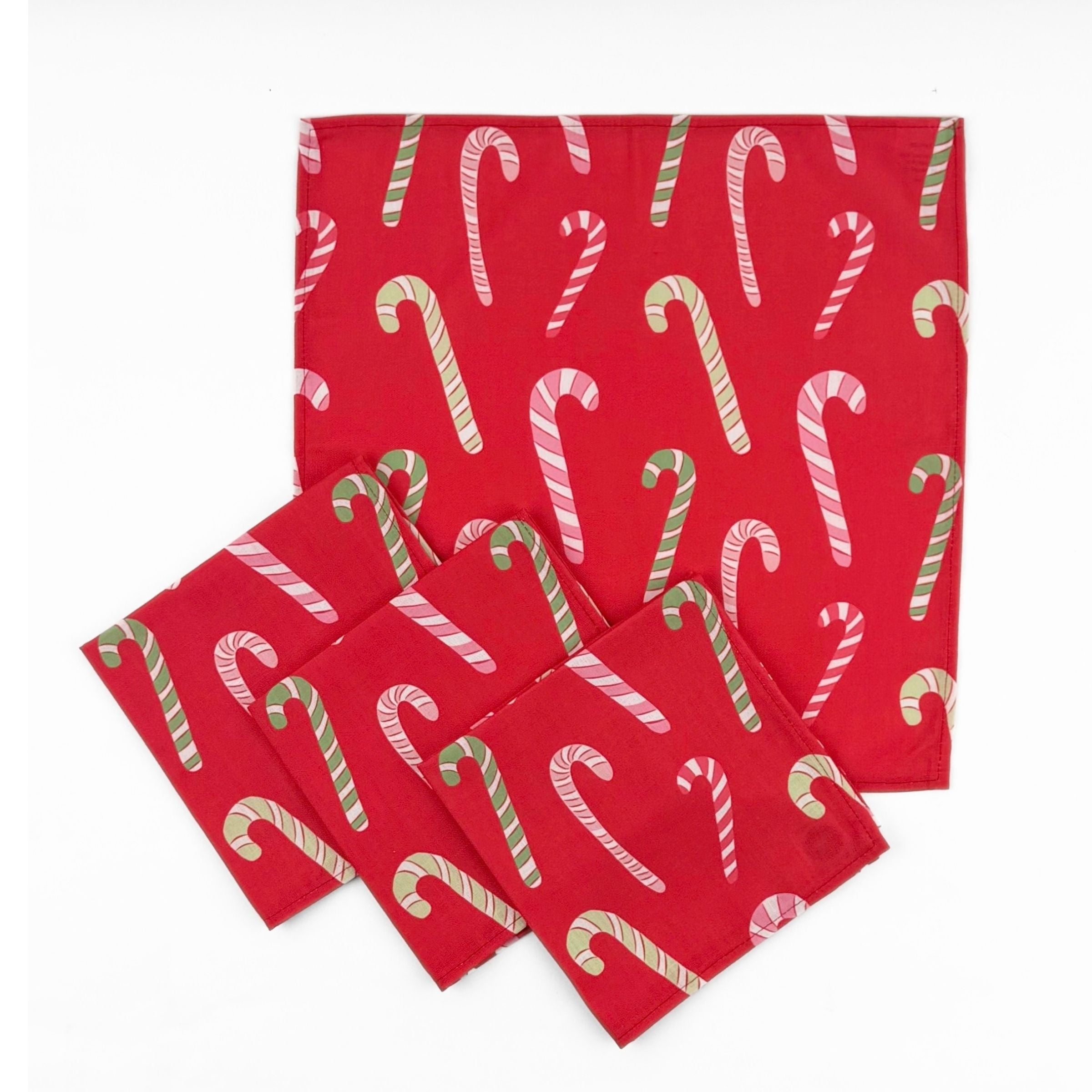 Set of Red cloth dinner napkins featuring playful pink, white, and green candy cane patterns for Christmas tablescapes.
