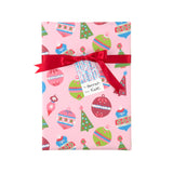 A gift box wrapped in pink Christmas-wrapping paper with a red ribbon and bow, featuring a personalized name tag that reads 'Hannah Kate'.