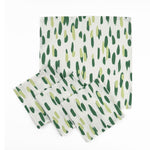 Set of White cloth dinner napkins featuring abstract green brushstroke patterns in varying shades for stylish tablescapes.