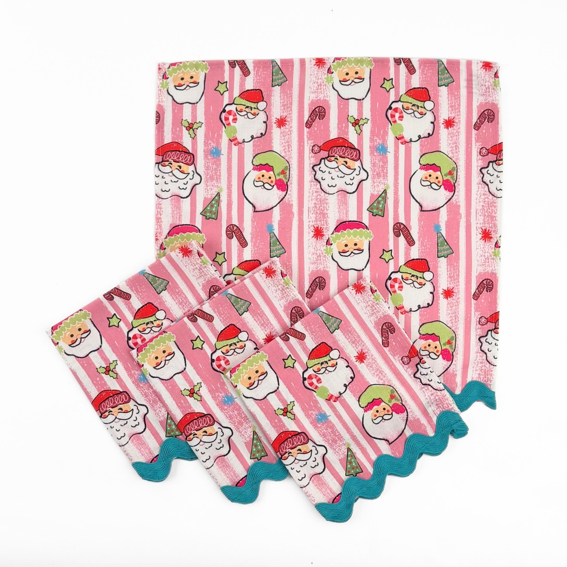 Set of Pink striped Christmas dinner napkins featuring cheerful Santa faces, festive motifs, and turquoise ric rac trim.