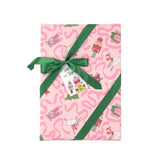 Pink christmas wrapping paper with a whimsical pattern of ballerinas, nutcrackers, and pink wavy lines, tied with a green ribbon and bow on a white background.