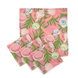 Set of Pink cloth dinner napkins featuring colorful seashells, tropical green foliage, and playful coastal inspired patterns.