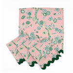 Set of Pink cloth dinner napkins featuring elegant green chinoiserie florals, delicate branches, and dark green trim.