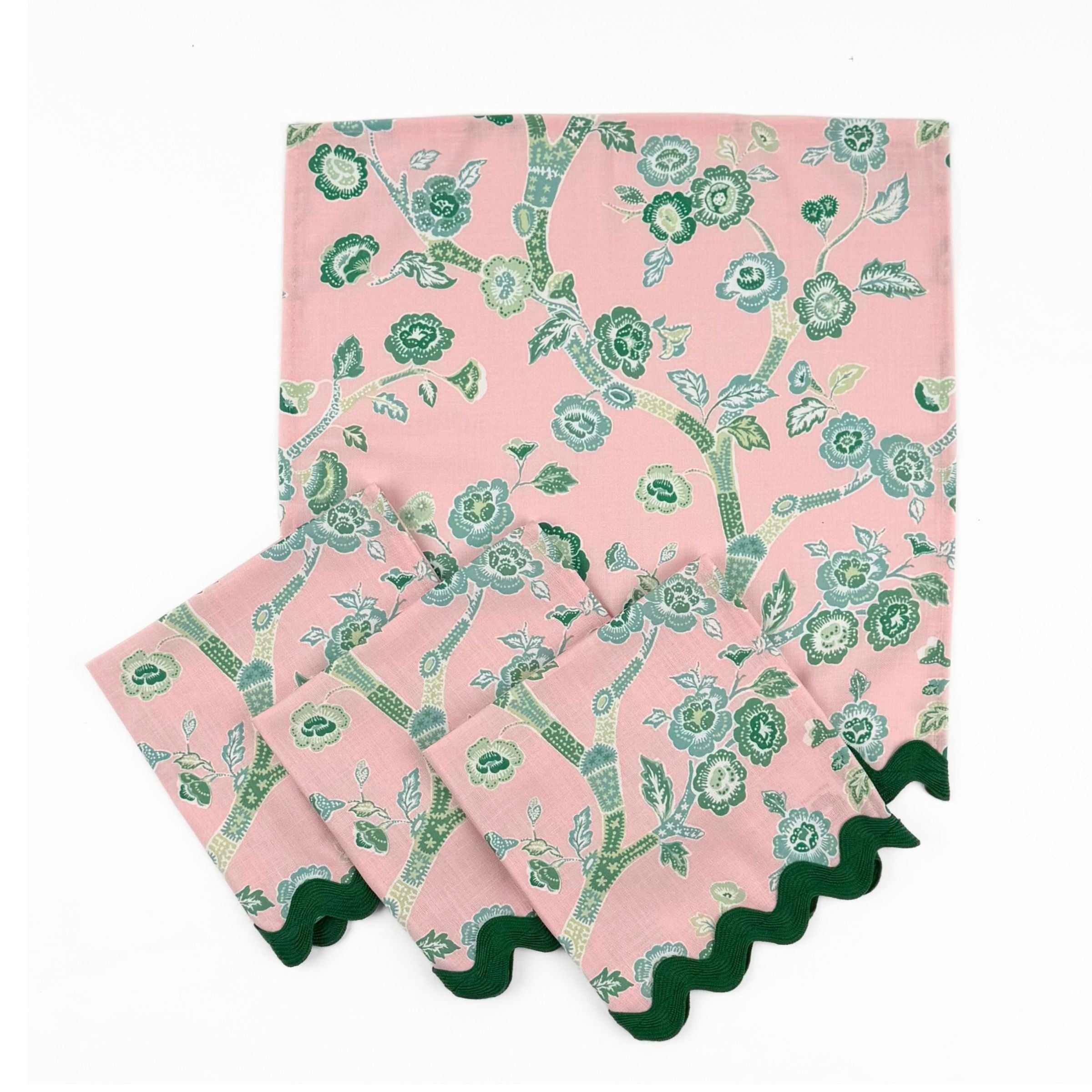 Set of Pink cloth dinner napkins featuring elegant green chinoiserie florals, delicate branches, and dark green trim.