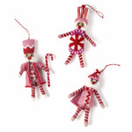 Three Christmas felt nutcracker ornaments in red, pink and white striped outfits on a white background