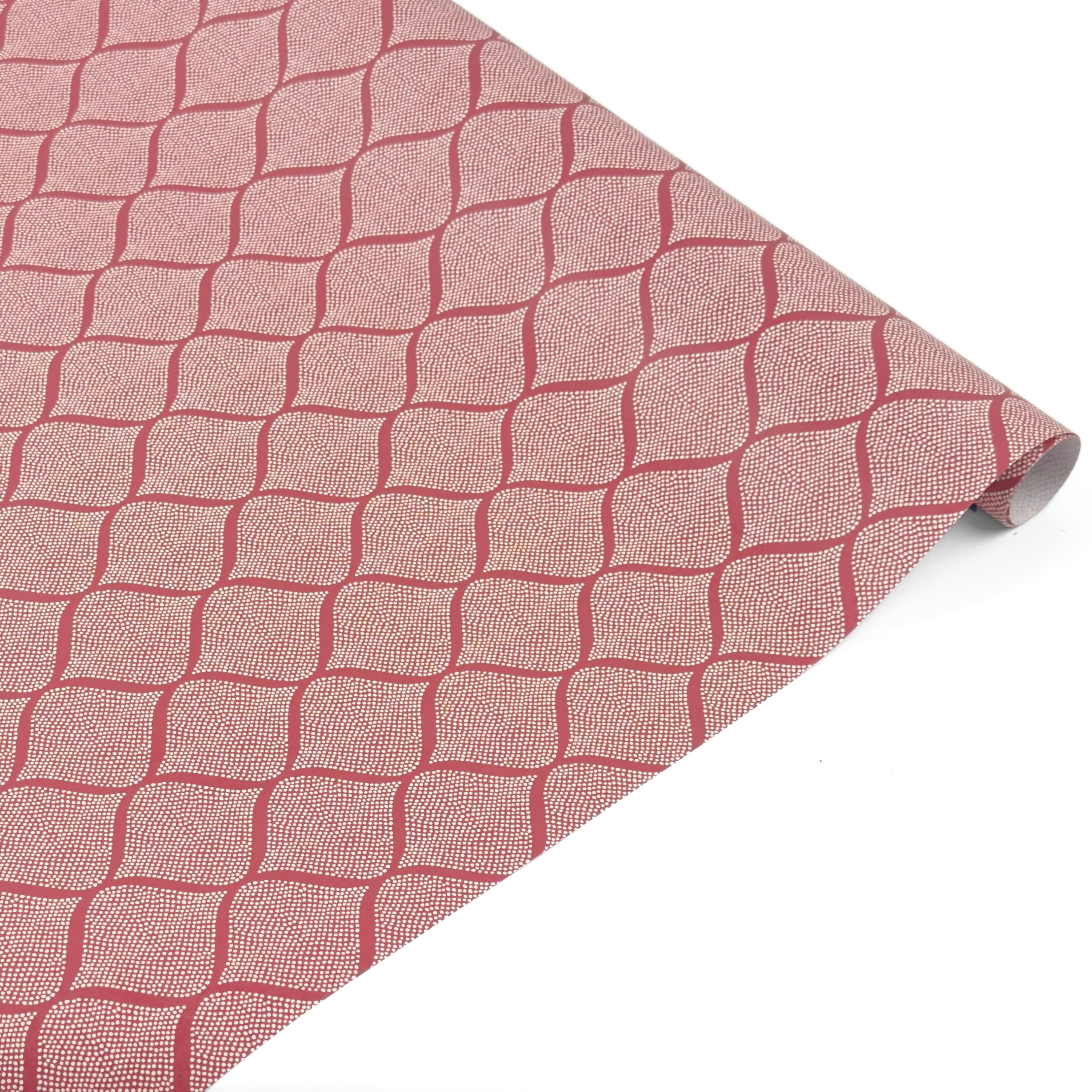 Rolled elegant gift wrapping paper featuring intricate red and white block print trellis patterns for beautiful presents.
