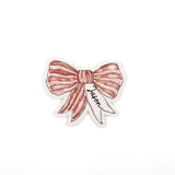 Elegant red bow place cards featuring delicate white stripes and personalized names for festive table settings.
