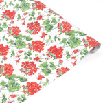 Roll of red geranium floral wrapping paper on a white background.