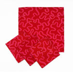 Set of Red cloth dinner napkins featuring playful pink swirling ribbon patterns, perfect for festive table settings.