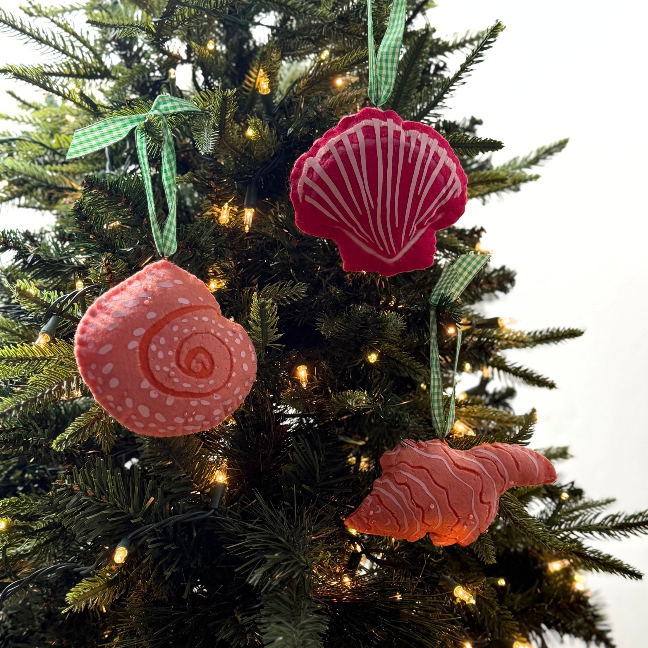 Handcrafted Pink Orange Shells Felt Christmas Ornaments featuring coral spiral, conch, and red scallop shell designs with green gingham ribbons.