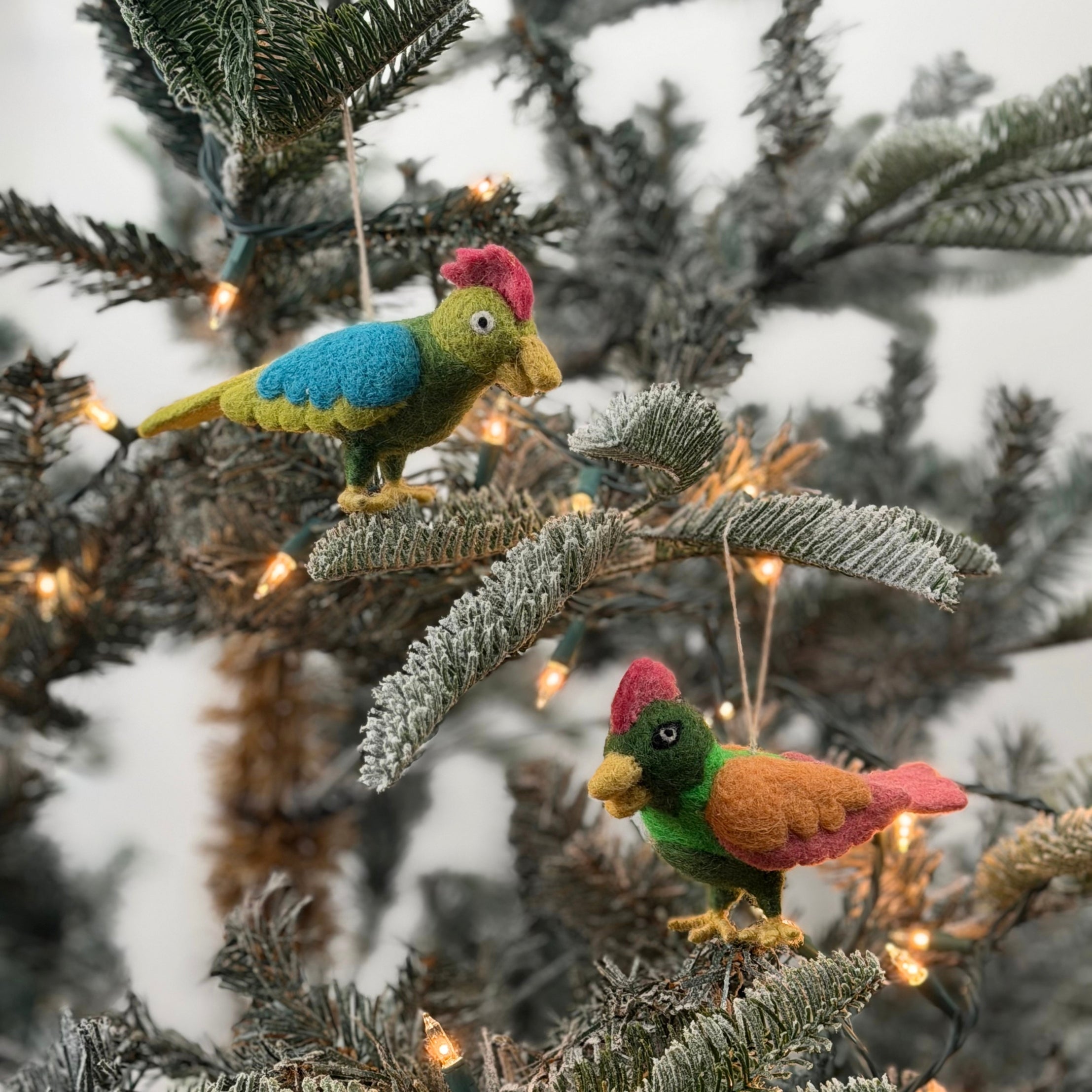 Felted wool Christmas bird ornaments featuring colorful feathers in green, blue, orange, and pink hues.