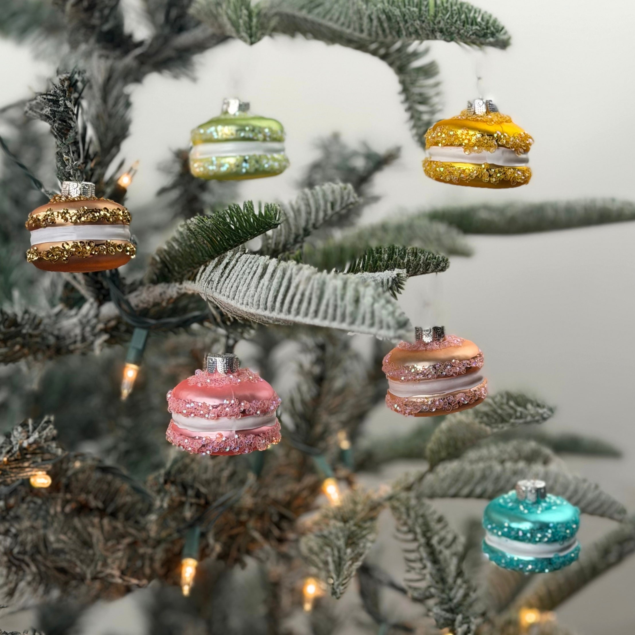 Colorful glass macaron Christmas ornaments featuring pastel shades, sparkling glitter accents, and elegant hanging loops.