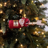 a santa riding a red champagne bottle ornament against a white background