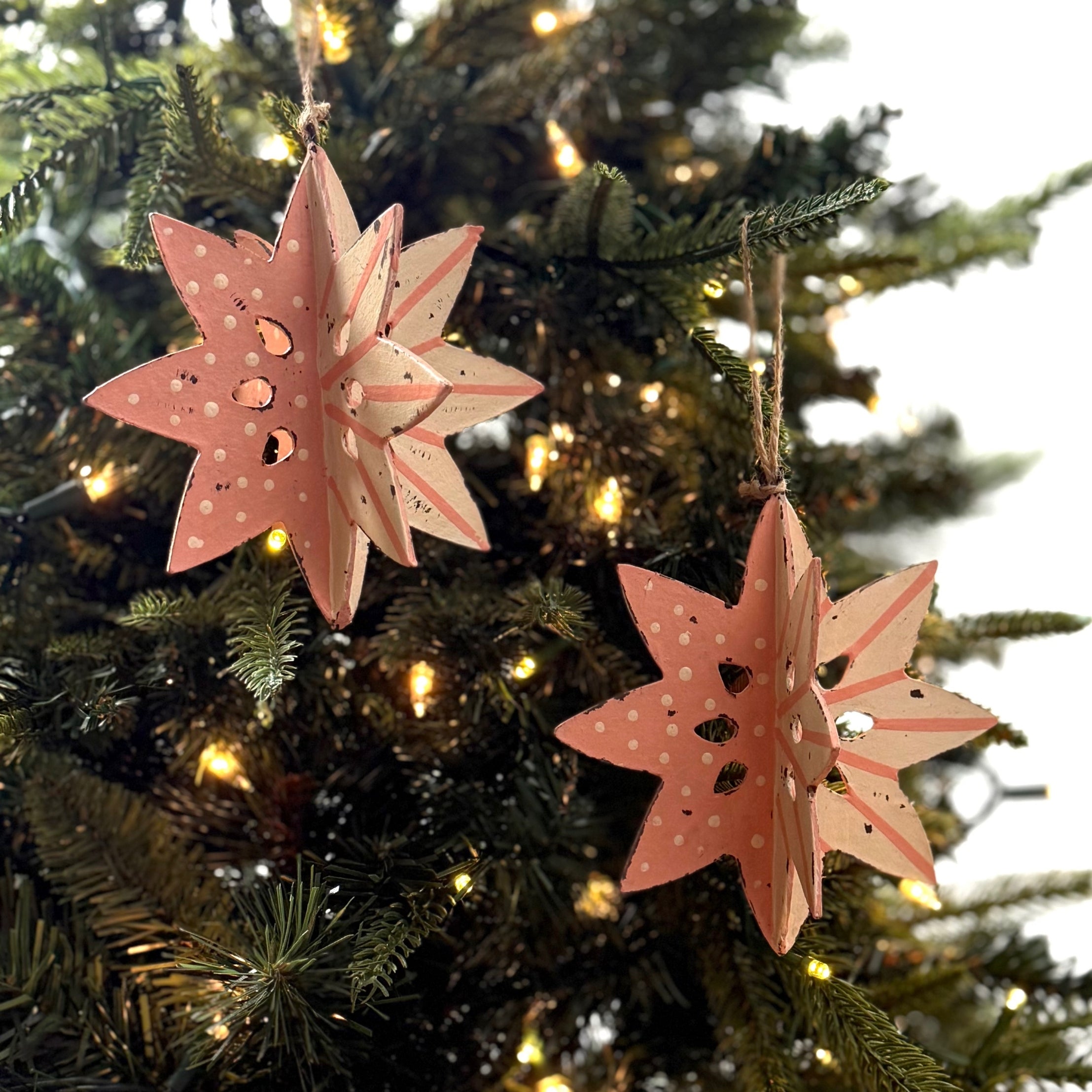 set of two large wooden star christmas ornaments painted in pink and white with distressed polka dot details