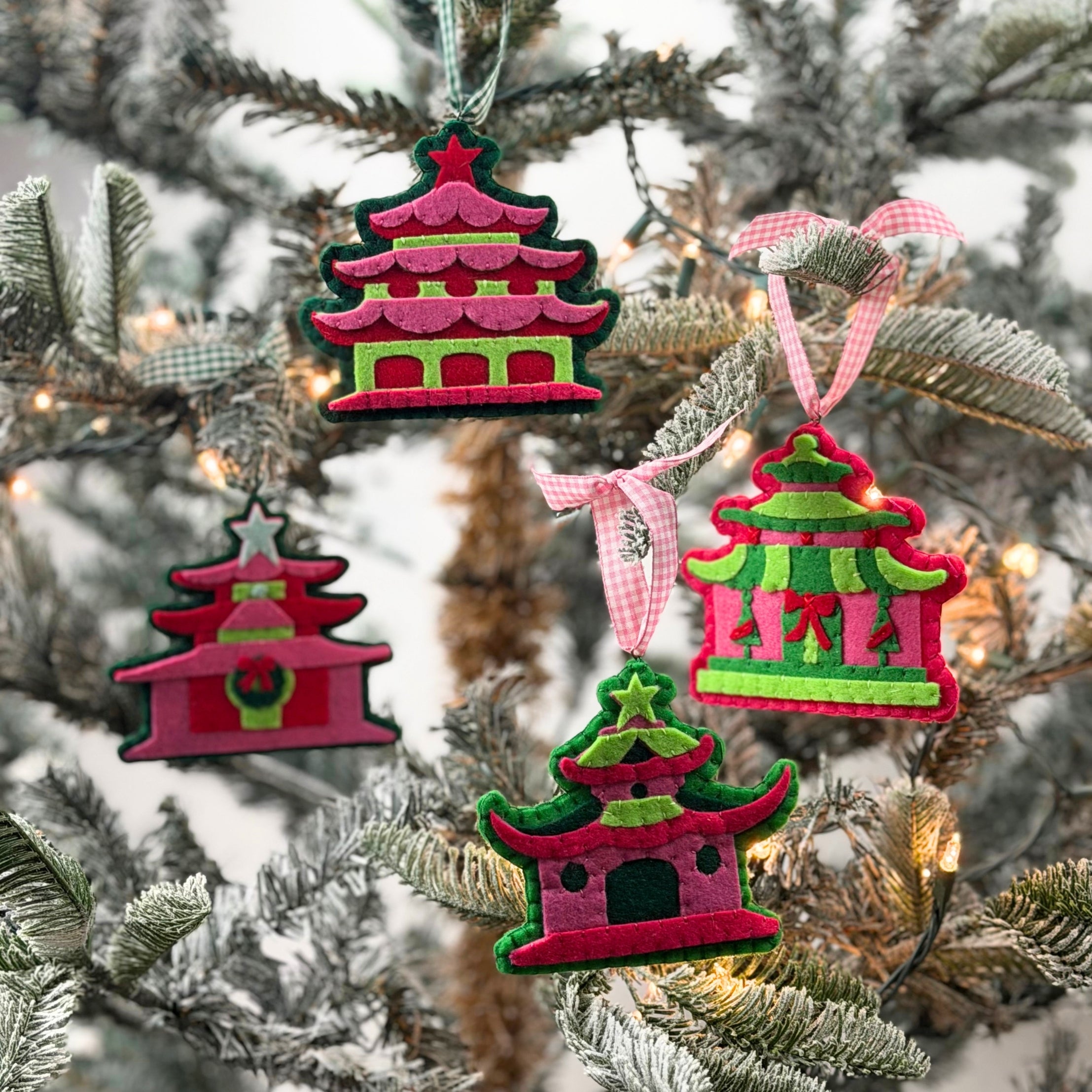 four pink felt chinoiserie christmas ornaments in the shape of pagodas against a white background 