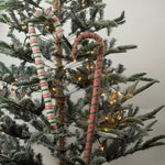 Large felt Christmas candy canes featuring festive pink, green, and cream stripes with playful patterns.