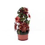A large metal handpainted Christmas candle holder featuring red poinsettia flowers and green holly leaves with a pink base. 