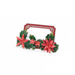 A metal christmas place card holder decorated with red poinsettia flowers and holly leaves and holding a red bordered white place card. 