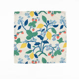 White cloth dinner napkins featuring vibrant strawberries, yellow lemons, blue flowers, and lush green foliage.