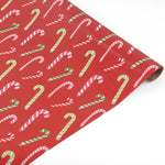 Red christmas wrapping paper with a repeating candy cane pattern, shown partially rolled on a white background.