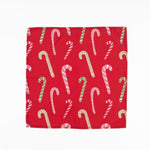 Red cloth dinner napkins featuring playful pink, white, and green candy cane patterns for Christmas tablescapes.